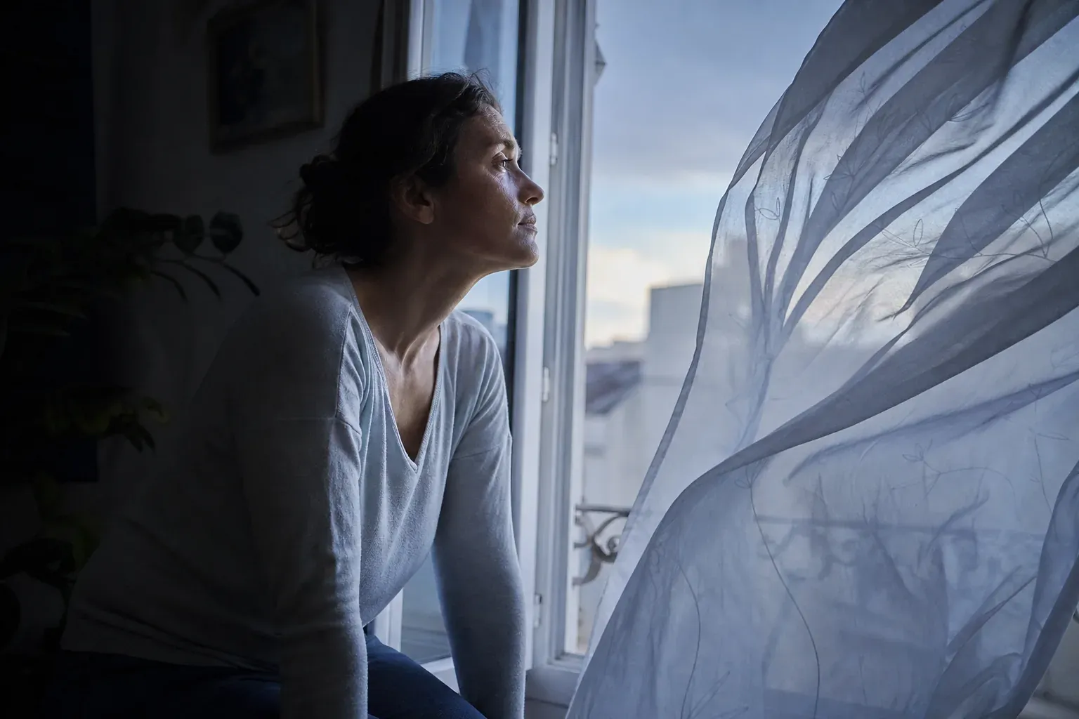 Femme prenant l air devant une fenetre ouverte