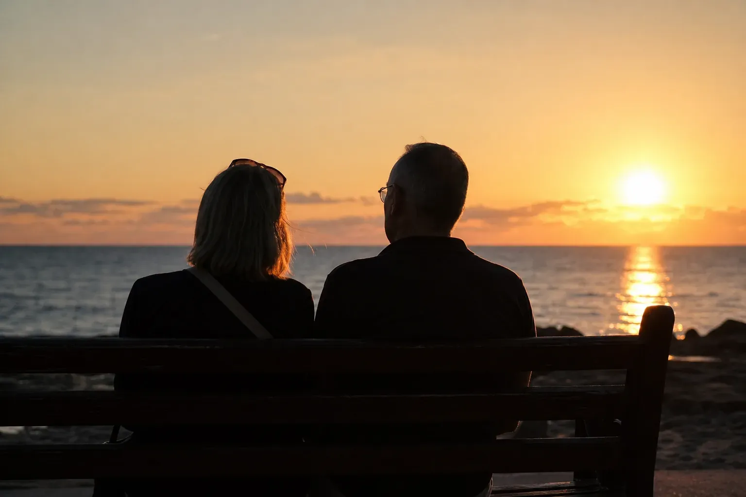 Couple mature assis de dos au coucher du soleil
